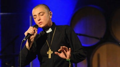 Sinead O'Connor singing with a clerical collar and cross on