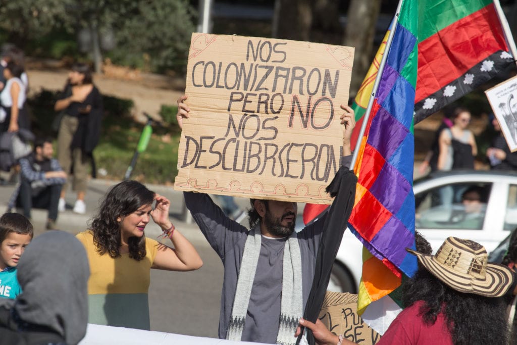 Guy holding a sign saying nos colonizaron pero no nos descuberceron at a protest