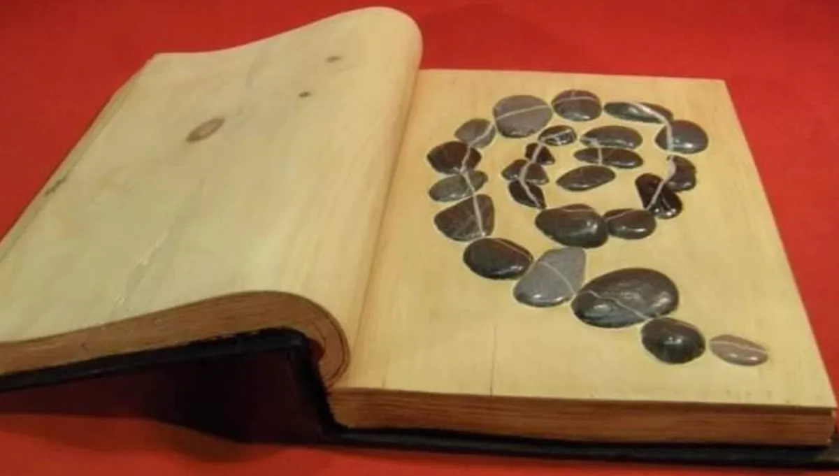 Wooden sculpture of a book with river stones spiraled inside