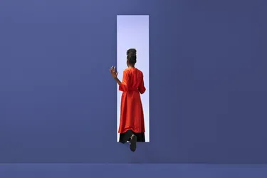 Black person with orange cloak stepping through portal in purple background
